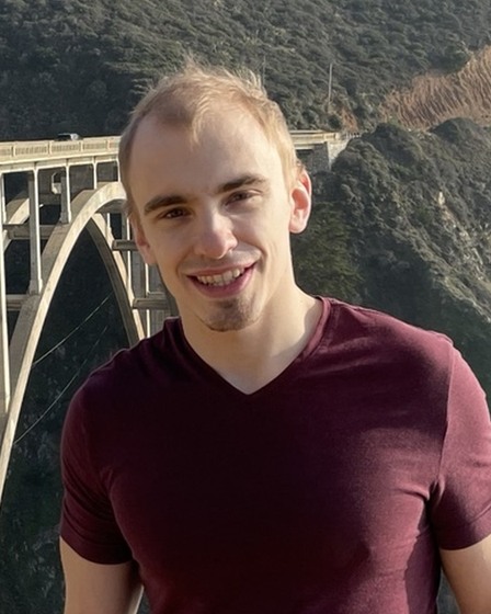Ben Krause smiling outdoors by a coastal bridge